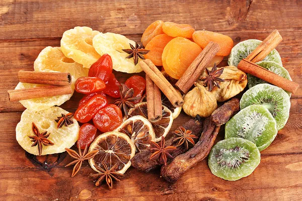 Dried fruits with cinnamon and anise stars on wooden background — Stock Photo, Image