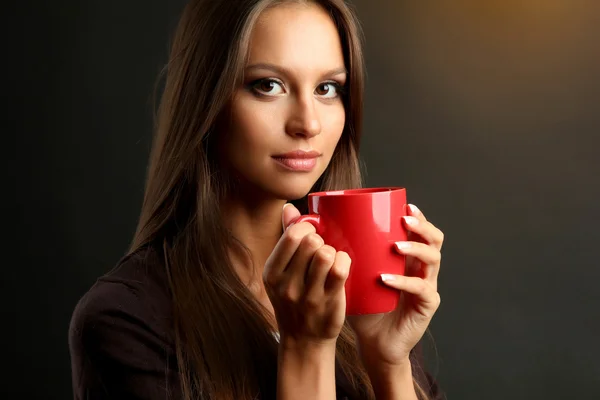 Bela jovem com xícara de café, no fundo marrom — Fotografia de Stock