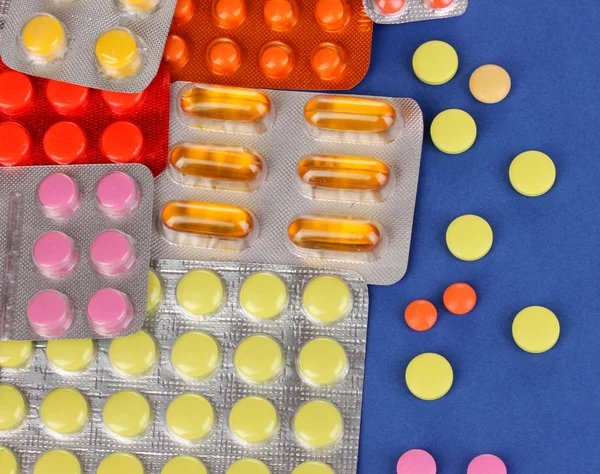 Capsules and pills packed in blisters on blue background — Stock Photo, Image