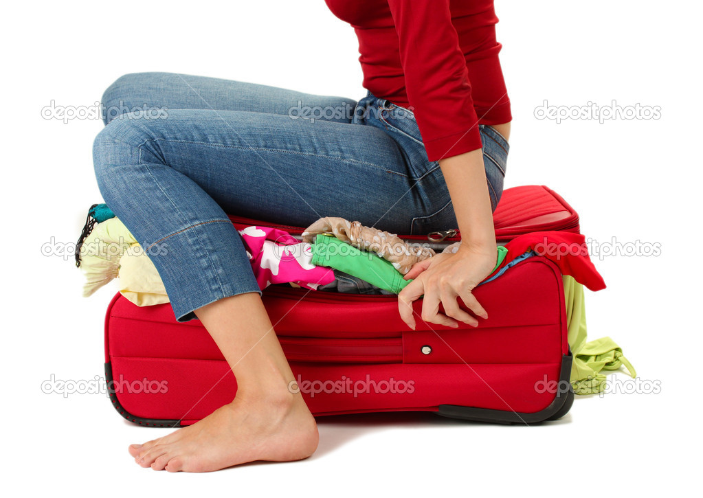 The girl is trying to close suitcase crammed on white background