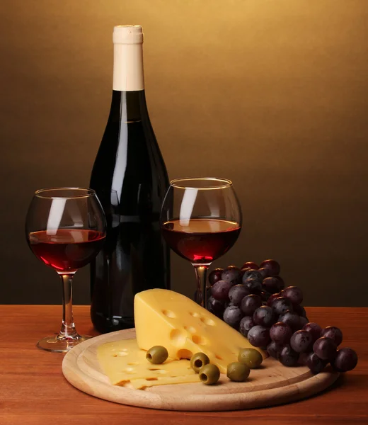 Garrafa de grande vinho com vinhedos e queijo em mesa de madeira sobre fundo marrom — Fotografia de Stock