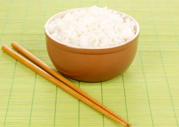 Bowl of rice and chopsticks on bamboo mat — Stock Photo, Image