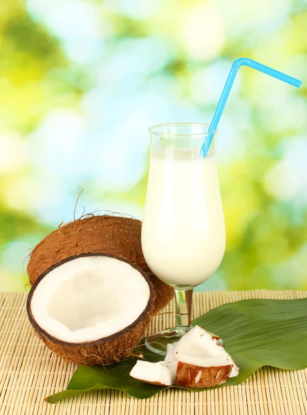 Glass of coconut milk and coconuts on green background close-up — Stock Photo, Image