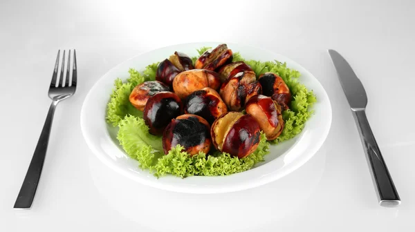 Roasted chestnuts with lettuce in the white plate with fork and knife isolated on white — Stock Photo, Image