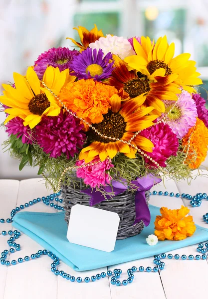 Beautiful bouquet of bright flowers with paper note on wooden table on window background — Stock Photo, Image