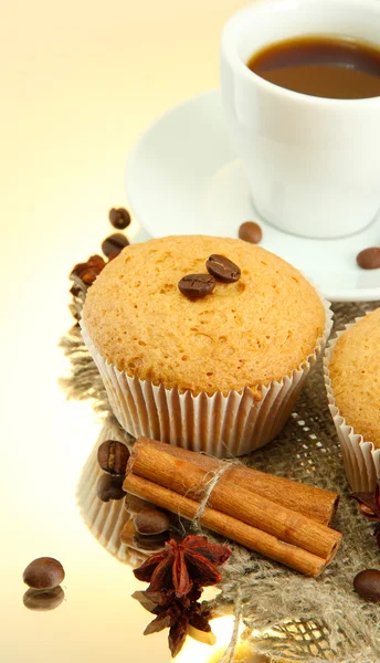 Tasty muffin cakes with spices on burlap and cup of coffee, on beige background — Stock Photo, Image