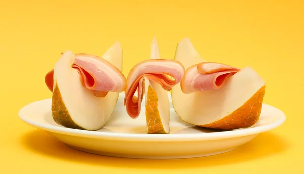 Parmaskinka och melon, på gul bakgrund — Stockfoto