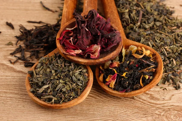 Assortment of dry tea in spoons, on wooden background — Stock Photo, Image