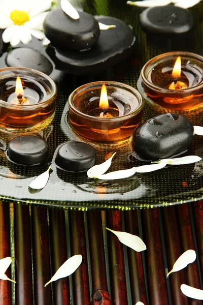 Piedras de spa con flores y velas en agua en el plato —  Fotos de Stock