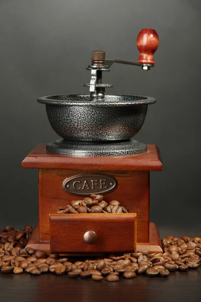 Mlýnek na kávu s kávová zrna na šedém pozadí — Stock fotografie