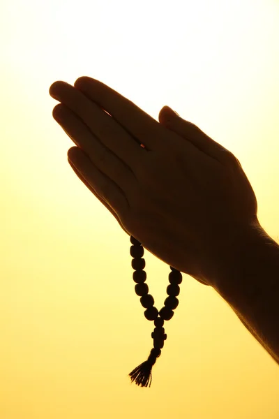 Male hands with rosary, on yellow background — Stock Photo, Image