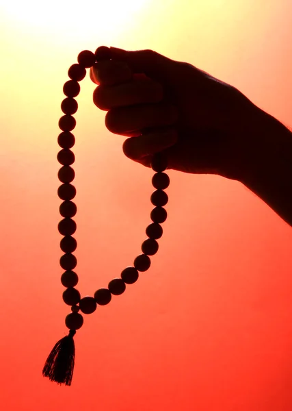 Mano maschile con rosario, su sfondo rosso — Foto Stock