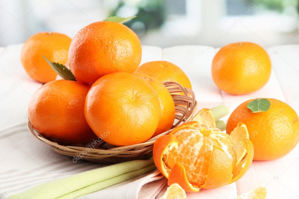 tangerines with leaves in a beautiful basket, on white wooden table