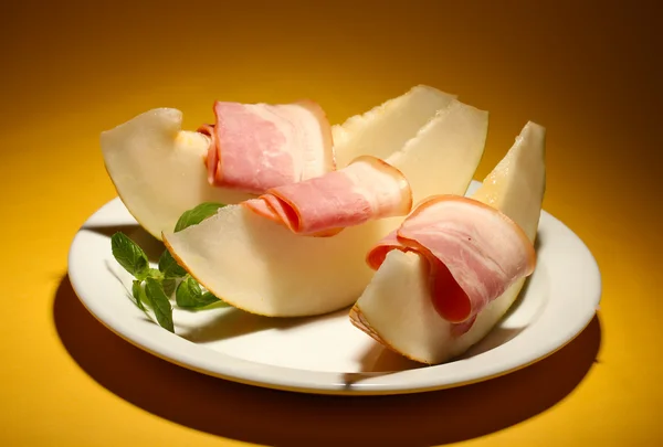 Parma ham and melon, on yellow background — Stock Photo, Image