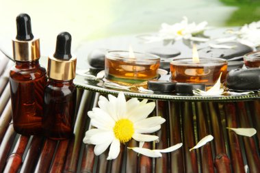 çiçekler ve mumlar tabakta su Spa taşlarla