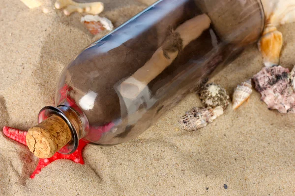 Glass bottle with note inside on sand — Stock Photo, Image
