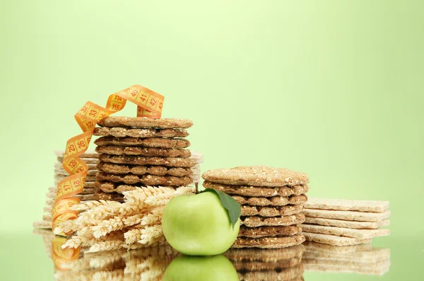 Вкусный хрустящий хлеб, яблоко и измерительная лента, на зеленом фоне — стоковое фото