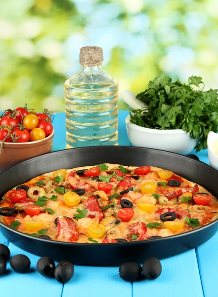 Färgglada sammansättning av läckra pizza, grönsaker och kryddor på blå trä bakgrund närbild — Stockfoto