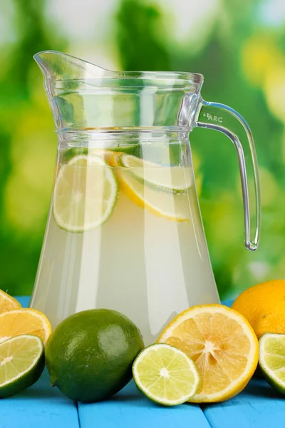 Zitruslimonade im Krug aus Zitrusfrüchten auf natürlichem Holztisch auf blauem Hintergrund — Stockfoto