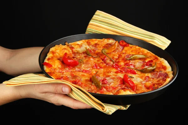Mãos que mantêm a pizza de pepperoni na panela isolada no preto — Fotografia de Stock