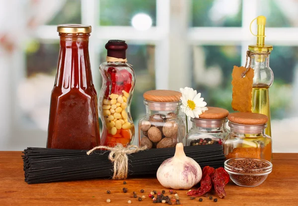 Pasta spaghetti, vegetables and spices on wooden table on bright background — Stock Photo, Image