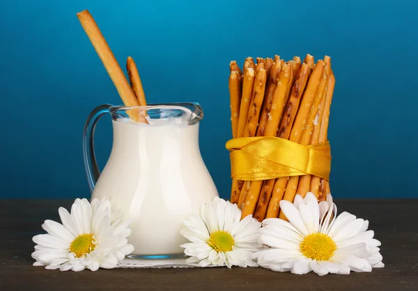 Tasty crispy sticks with pitcher with sour cream on wooden table on blue background — Stock Photo, Image