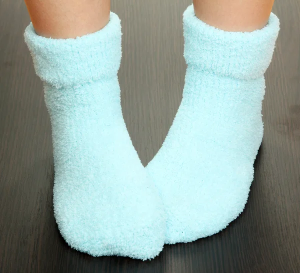 Benen vrouwelijke in blauwe sokken op laminaat vloer — Stockfoto