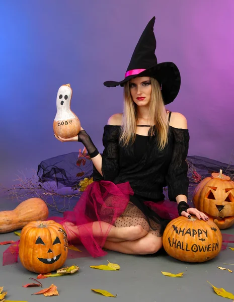 Halloween-Hexe hält Kürbis auf farbigem Hintergrund — Stockfoto