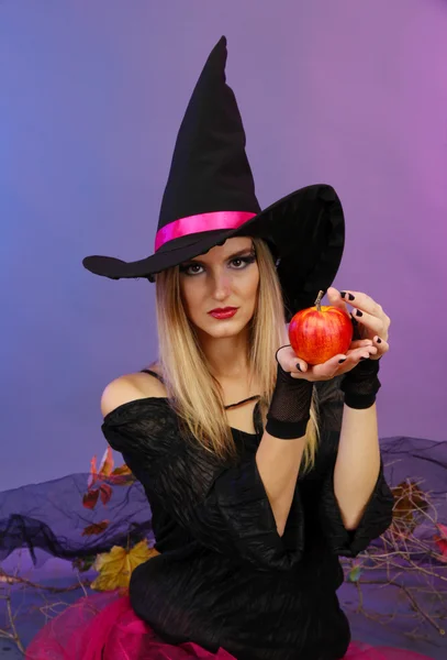 Halloween witch with red apple on color background — Stock Photo, Image