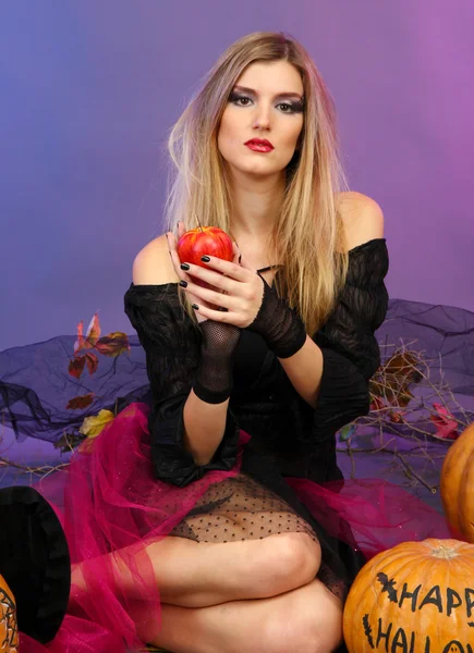 Halloween-Hexe mit rotem Apfel auf farbigem Hintergrund — Stockfoto