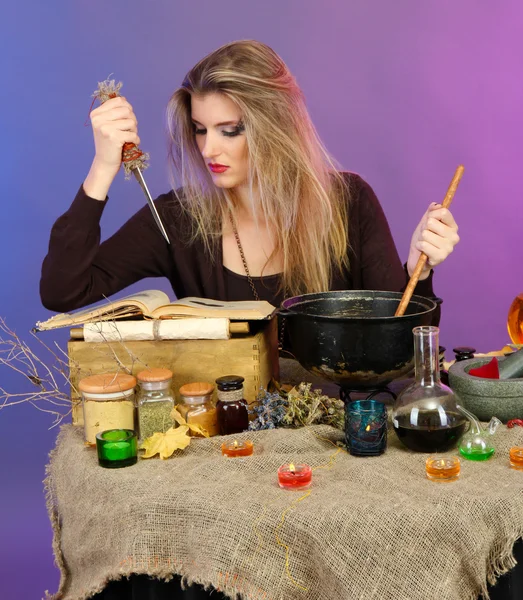 Halloween witch stirring in poison soup in her cauldron on color background — Stok fotoğraf