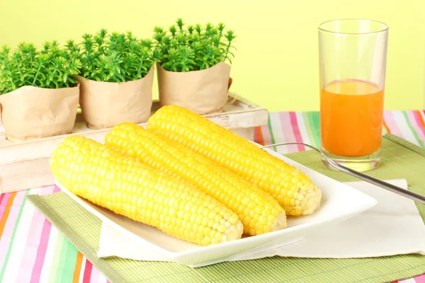 Boiled corn and juice on a green background — Stock Photo, Image