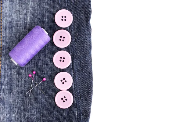 Boutons à coudre colorés avec fil sur jeans isolés sur blanc — Photo