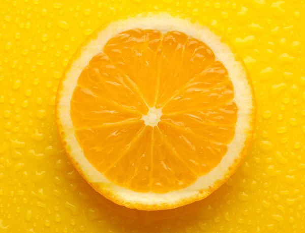 Tranche d'orange avec goutte sur fond jaune — Photo