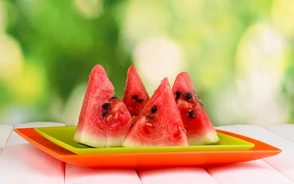 Zoete watermeloen segmenten op platen op houten tafel op natuurlijke achtergrond — Stockfoto