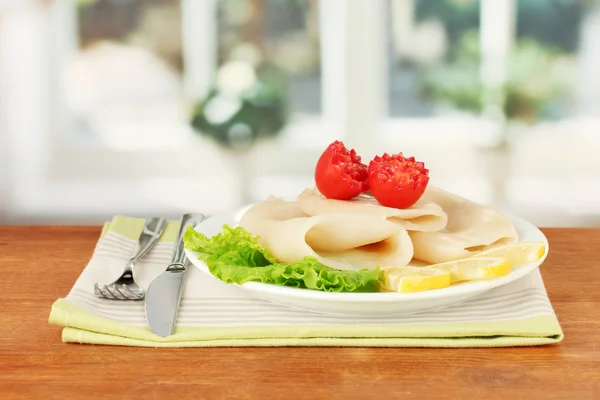 Вареные кальмары с овощами на тарелке на деревянном столе крупным планом — стоковое фото