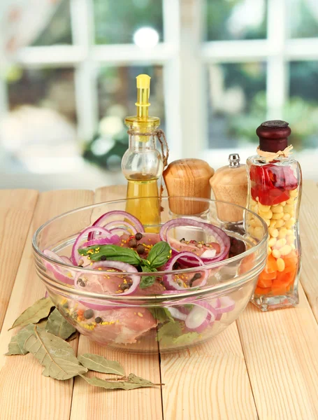 Un gran trozo de cerdo marinado en un tazón con hierbas, especias y aceite de cocina sobre una mesa de madera sobre un fondo de ventana —  Fotos de Stock