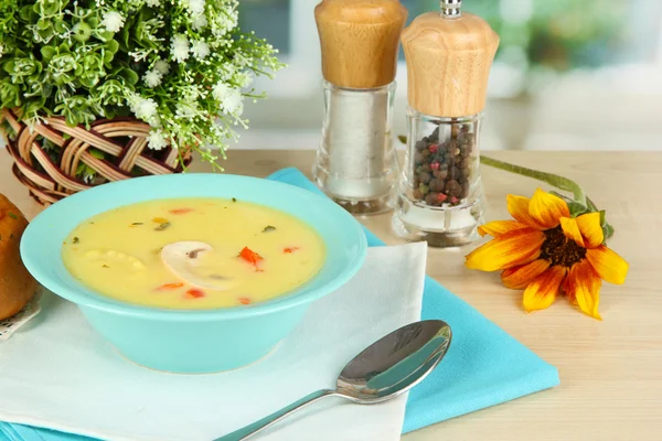 Ароматный суп в голубой тарелке на столе на фоне окна крупным планом — стоковое фото