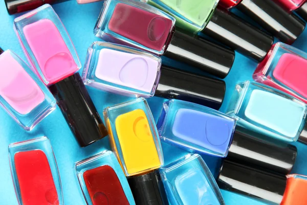 Group of bright nail polishes, on blue background — Stock Photo, Image