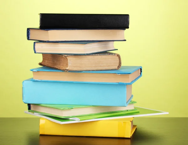 Stapel interessante boeken en de tijdschriften op houten tafel op groene achtergrond — Stockfoto