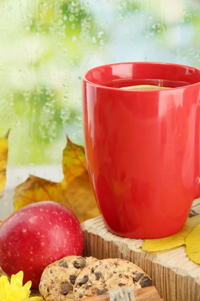 Cup of hot tea and autumn leaves, on rain background — Stock Photo, Image