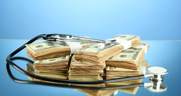 Концепция затрат на здравоохранение: стетоскоп и доллары на цветном фоне — стоковое фото