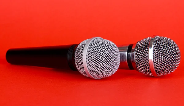 Srebrny i czarny mikrofony na czerwonym tle — Zdjęcie stockowe
