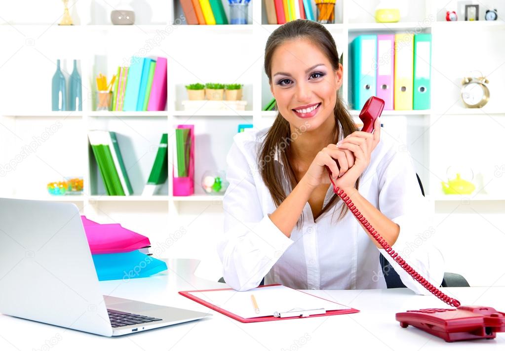 Young pretty business woman with phone and notebook working at office