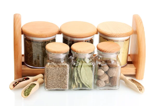 Jars and wooden spoons on shelf with spices isolated on white — Stock Photo, Image