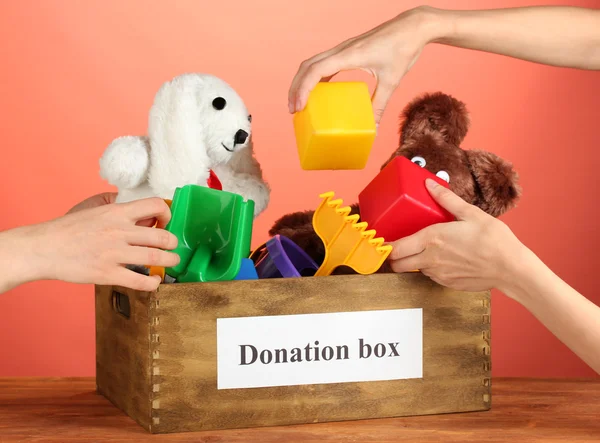 Caixa de doação com brinquedos para crianças no fundo vermelho close-up — Fotografia de Stock