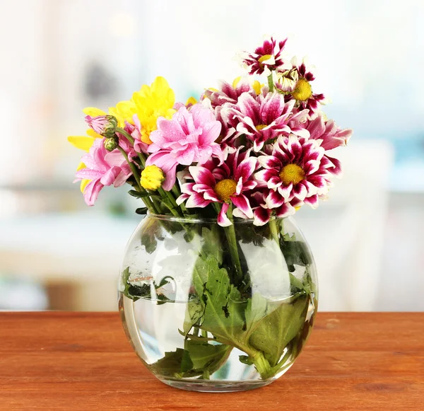 Barevné kytice chryzantém v skleněné vázy na dřevěný stůl detail — Stock fotografie