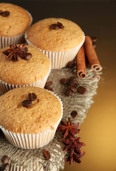 Tasty muffin cakes on burlap, spices and coffee seeds, on brown background — Stock Photo, Image