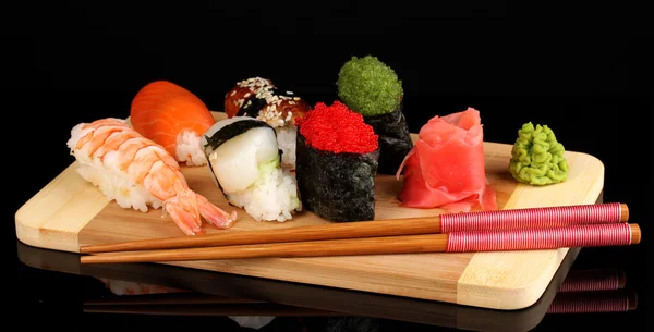 Delicioso sushi servido en tablero de madera aislado en negro — Foto de Stock