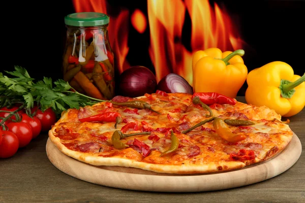 Smaczne pepperoni pizza z warzywami na desce na tle płomień — Zdjęcie stockowe